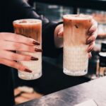 Cafes - Two people holding up two glasses of coffee